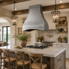 Transitional rustic kitchen with a hammered zinc range hood obove a kitchen island with a gas stove
