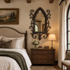 Gothic wrought iron mirror with quatrefoil tracery displayed in a refined bedroom interior
