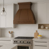 Copper range hood with a floral motif in a modern kitchen with relief detailing and clean cabinetry with contemporary finish