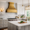 Handcrafted brass range hood with a horizontal strap in a transitional kitchen with clean lines and warm wood accents