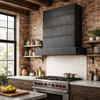 Rectangular zinc range hood with riveted bands in industrial loft kitchen with brick wall and dark cabinets