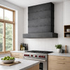 Rectangular zinc range hood with riveted bands in Scandinavian modern kitchen with light wood cabinets and white walls