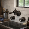 Solid brass wall mounted faucet with exposed industrial geometry and wheel handles in a small bar bathroom, three piece setup over wall basin