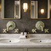 Solid brass wall mounted faucet with verdigris patina in a hotel guest room washroom above a marble vanity and framed mirror