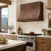 Hand-Hammered Copper Range Hood with Adjustable Strap Layout in a mountain lodge kitchen with exposed wood beams and stone accents
