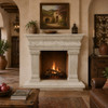 Carved cantera stone fireplace mantel with classical columns in a rustic hacienda interior
