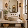 Round cantera stone vessel sink in Mediterranean powder room with arched mirror and bronze wall sconces