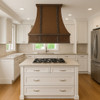 Spanish Colonial Revival island copper range hood in USA suburban kitchen, hammered canopy with warm patina above island cooktop and classic finishes