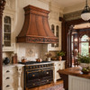 Victorian scroll copper range hood in a Queen Anne residence kitchen with ornate woodwork and cream cabinetry
