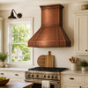 Retro Hammered Copper Range Hood above stainless steel range in American suburban kitchen with off white cabinets and window