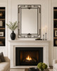 Art Deco Iron Mirror with Stepped Geometric Frame positioned above a stone fireplace mantel