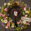 Handmade Mexican heart ornament with dog motif displayed on a colorful spring floral wreath