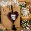 Handmade Mexican heart ornament with dog motif attached to a kraft gift bag as reusable decor