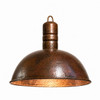 Hand-hammered copper dome pendant lamp with aged patina finish and light on, on white background