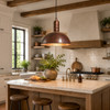 Hand-hammered copper dome pendant lamp above a bright farmhouse kitchen island with wood cabinetry and stone countertop