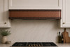 Hammered copper under cabinet range hood with dark bronze straps and rivets cluse up
