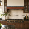 Hammered copper range hood with riveted zinc bands in an Art Deco revival kitchen