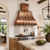 Copper bell range hood with polished zinc straps in a Modern Hacienda kitchen