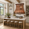 Modern farmhouse kitchen with polished copper range hood, zinc straps, white cabinetry, oak island and marble counters