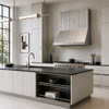 Riveted three-bay natural zinc range hood in a bright Bauhaus-inspired kitchen with flat-panel cabinetry and black stone