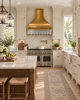 Brass range hood with zinc apron and iron frame in a Traditional American kitchen with cream cabinetry and marble counters