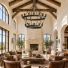 Two-tier iron chandelier in a bright vaulted great room with timber beams, stone fireplace, and leather seating