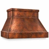 Angled view of a hand-hammered copper range hood showing its tapered canopy, wide apron, and box chimney