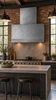 Rectangular hand-hammered zinc hood in an industrial kitchen with exposed brick, concrete, and dark steel details