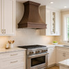Custom hammered copper range hood installed in a transitional kitchen