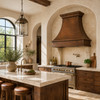Mediterranean kitchen with hammered copper range hood, limestone backsplash, walnut cabinetry and arched windows