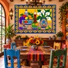 Talavera fruit and lily tile mural featured in a rustic dining room with colorful pottery