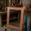 Hammered copper rectangular mirror frame being hand-shaped by a coppersmith in a Mexican workshop
