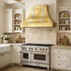 Mixed metal tin range hood with zinc straps in French Country kitchen with warm stone, painted cabinets, polished sheen