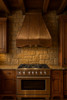 36 inch pyramid shape copper hood for gas stove in rustic kitchen, warm patina canopy above range with wood beams and stone backsplash