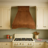 Pyramid shape copper hood for gas stove in 1950s style kitchen, warm patina canopy above range with retro cabinets and tiled backsplash