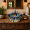 Mexican talavera fish floral round bath sink in a Spanish Revival bathroom vanity with warm tones and natural light