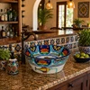 Mexican talavera fish floral round bath sink styled in a kitchen bar area with handcrafted accents and open layout