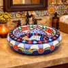 Talavera floral arch vessel Mexican bathroom sink featured in a restaurant bathroom with decorative tile walls and warm ambiance