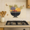 Mexican tile mural fruit bowl displayed on a kitchen wall backsplash with warm Spanish Revival decor
