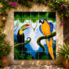 Toucan and macaw talavera tile mural on a garden wall surrounded by flowers and greenery.