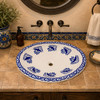 Oval mexican bathroom sink cobalt bird design installed in Spanish Revival bathroom with wrought iron mirror and tile wall