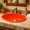 Mexican oval orange talavera bathroom sink in Spanish Revival bathroom with stucco walls and wrought iron accents