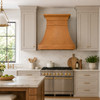 Honey patina copper range hood in transitional kitchen with shaker cabinets, quartzite surfaces and brass hardware