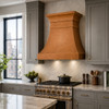 Honey patina copper range hood in New York style kitchen with gray cabinetry, marble surfaces and city window