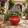 Red ceramic Talavera planter styled with lush foliage in a Mediterranean garden setting