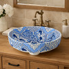 Talavera blue floral above counter bathroom sink in bathroom vanity with wood cabinet and warm lighting