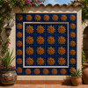 Mexican relief tile – sun face motif displayed on garden patio wall framed by stucco and plants