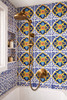 Yellow blue talavera medallion tile applied to a shower wall highlighting symmetry and rich hand painted detail