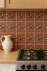 Talavera mexican tile with a floral central accent on a terracotta background installed on a kitchen wall adding rustic warmth with hand-painted floral motif accents