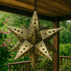 Punched tin star lamp shade with intricate cut-out patterns hanged on a veranda